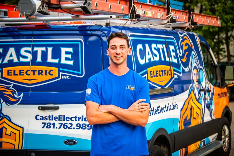 Castle Electric tech standing in front of service van