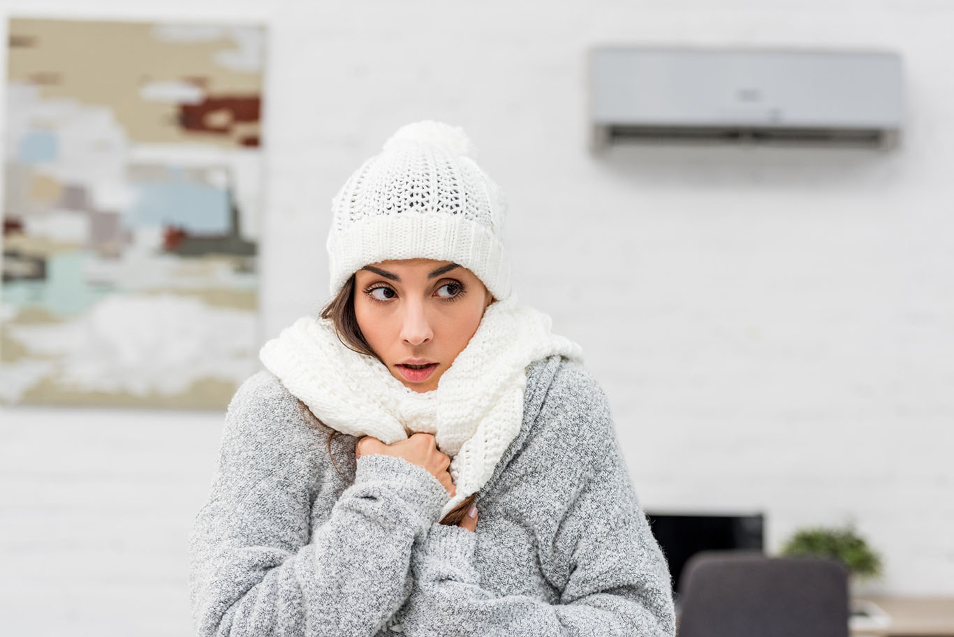 woman wearing hat, scarf and jacket inside because heater is broken