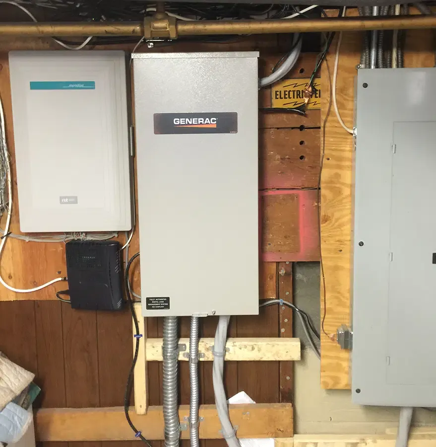 Generac automatic transfer switch installed in residential basement by Castle Electric, with electrical panel and load management system