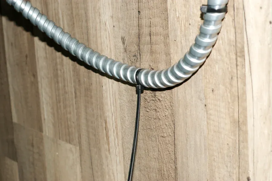 Unsafe BX armored cable wiring during removal in an older home, highlighting damaged electrical conduit and the fire and shock hazards associated with outdated armored cable systems.