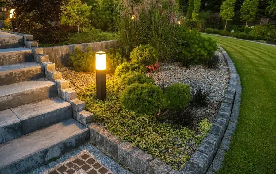 Professional outdoor landscape lighting installation illuminating a residential walkway and garden, enhancing curb appeal, safety, and nighttime visibility for homeowners.