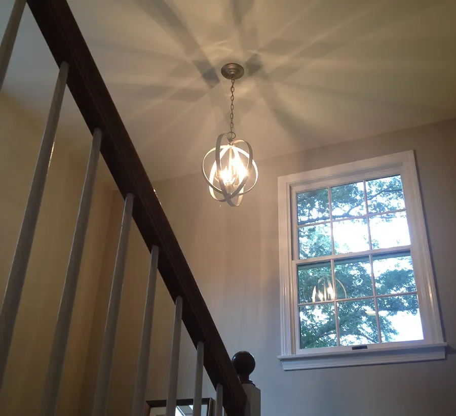 Metal orb pendant chandelier installed over stairwell by licensed electrician in Eastern Massachusetts