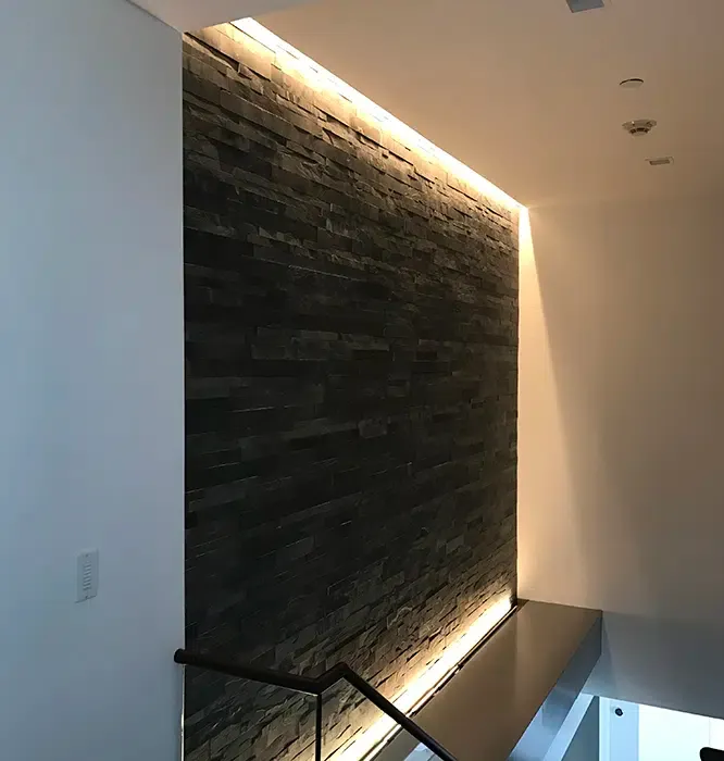 Top and bottom LED cove lighting highlighting a dark stone accent wall by Castle Electric in Eastern MA