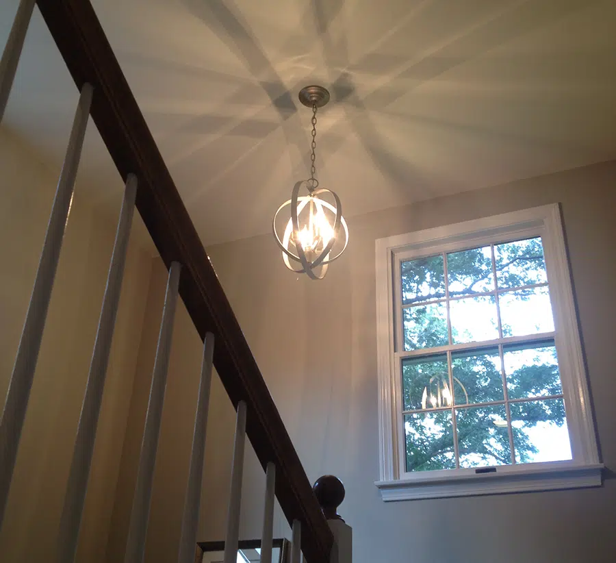 Metal orb pendant chandelier installed over stairwell by licensed electrician in Eastern Massachusetts