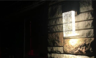 Modern outdoor LED wall sconce installed on stone exterior by Castle Electric serving Greater Boston MA